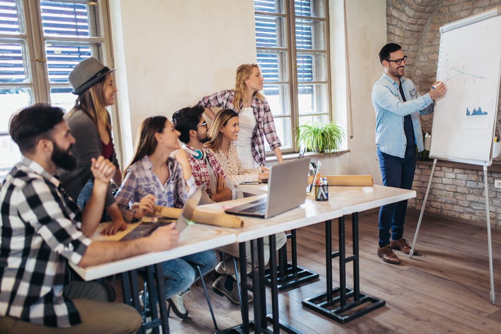 Business team collaborating while man draws on white board